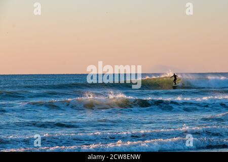 Surfista godendo di un surf al tramonto in California Foto Stock