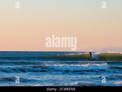 Surfista godendo di un surf al tramonto in California Foto Stock