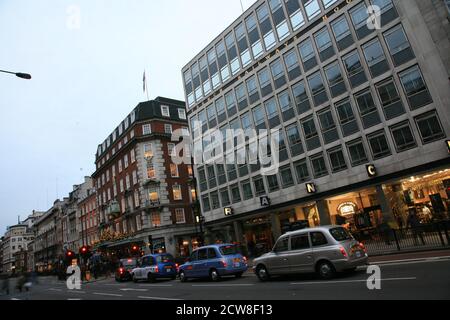 Londra, Regno Unito - 13 novembre 2010: Taxi nella strada di Londra. Passeggero donna con borse per la spesa che chiede all'autista prima di salire a bordo. Le cabine nere sono il Foto Stock