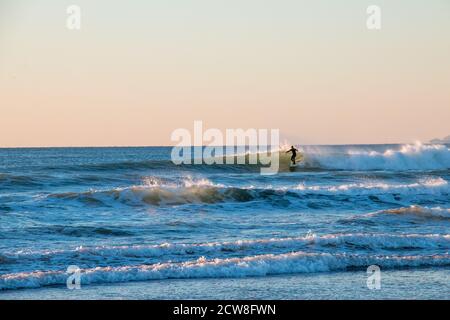 Surfista godendo di un surf al tramonto in California Foto Stock