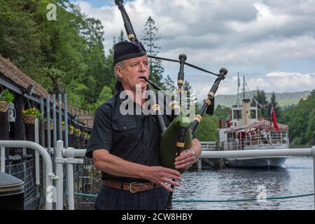 Scottish Bagpiper suonando cornamuse vicino ad un lago Foto Stock