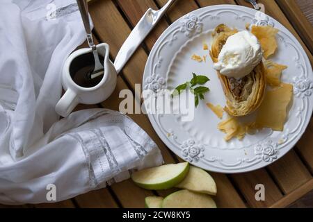 strudel di mele con una paletta di gelato alla vaniglia, menta su un piatto di vetro bianco. Foto Stock