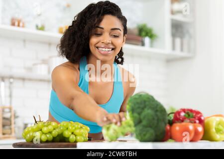 Felice giovane femmina nero modello di preparazione insalata di verdure Foto Stock