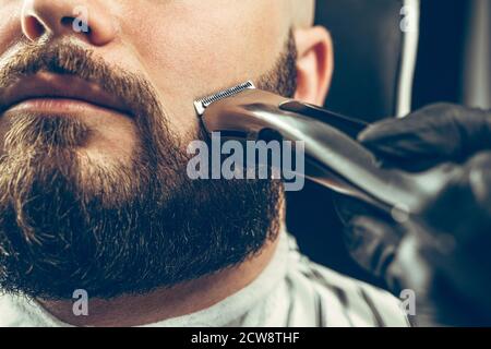 Cliente barbiere. L'uomo ha rifinito la barba con un rasoio elettrico Foto Stock