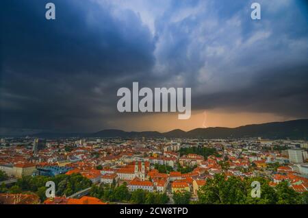 Tempesta di fulmini con spettacolari nuvole sulla città di Graz, con la chiesa di Mariahilfer e gli edifici storici, nella regione della Stiria, in Austria Foto Stock