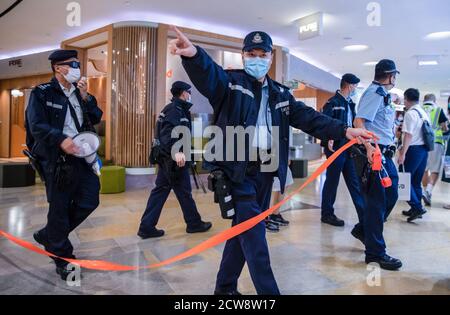 Un poliziotto che indossa una maschera cordoni fuori dalla zona con nastro rosso dopo che i manifestanti hanno cantato e cantato slogan a loro durante la protesta per commemorare il 6 ° anniversario del movimento Umbrella.dozzine di manifestanti pro-democrazia si sono riuniti al centro commerciale Pacific Place a Hong Kong per celebrare il 6 ° anniversario Del movimento di Umbrella dove Hong Kongers ha preso alla strada ed ha occupato le strade principali nella città per richiedere il suffragio universale. Foto Stock