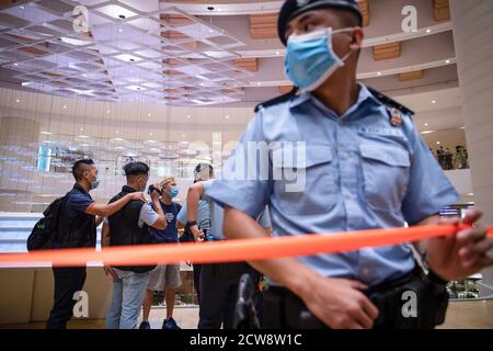 Un poliziotto che indossa una maschera cordoni fuori dall'area con nastro rosso mentre controlla l'identificazione dei manifestanti durante la protesta per commemorare il 6 ° anniversario del movimento Umbrella.dozzine di manifestanti pro-democrazia si sono riuniti al centro commerciale Pacific Place a Hong Kong per celebrare il 6 ° anniversario del movimento Umbrella dove Hong Kongers ha preso in strada e occupato le strade principali della città per richiedere il suffragio universale. Foto Stock