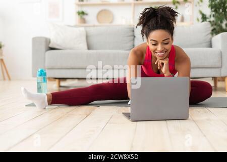Fit African American Woman esercitando al laptop Training a casa Foto Stock