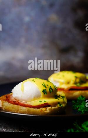 Uova Benedict fatte in casa con uova in camicia perfetta pancetta canadese condita con salsa Hollandaise, fuoco selettivo Foto Stock