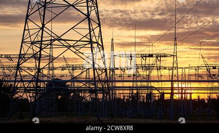 Le sagome dell'infrastruttura di trasmissione della centrale elettrica al tramonto. Foto Stock