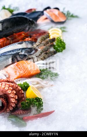 Vista laterale di una varietà di pesce fresco di lusso, aragosta salmone sgombro gamberi polpo di gamberi, cozze e capesante, su fondo ghiaccio con fumo ghiacciato in s. Foto Stock