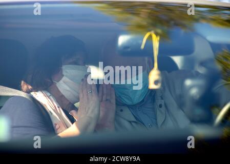 Felice coppia anziana che indossa maschere anti virus stanno guidando dentro Un'auto durante la pandemia COVID-19 Foto Stock