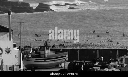 Nave del pescatore vicino alla spiaggia che si prepara ad andare a pesca con sufers in background Foto Stock