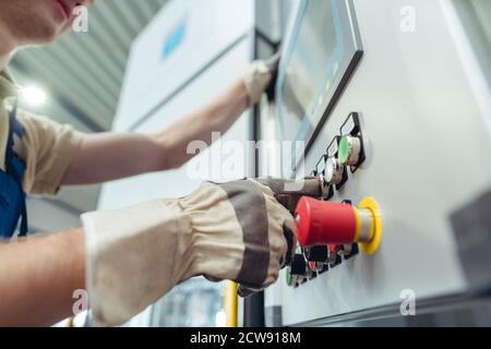 Addetto alla produzione premendo il pulsante della macchina di piegatura del metallo Foto Stock