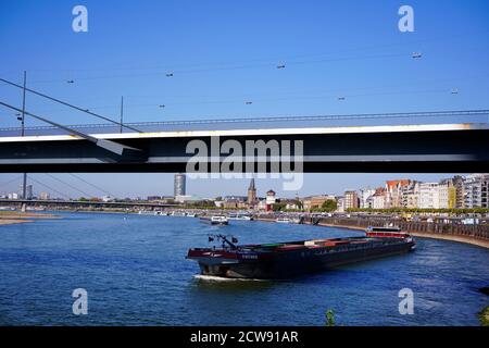 Skyline del fiume Reno a Düsseldorf con la nave che passa sotto il ponte Rheinknie. Foto Stock