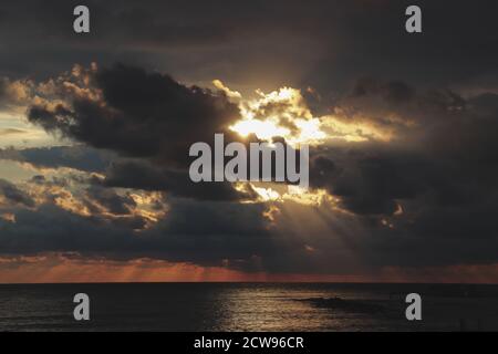 Sole tra le nuvole al tramonto sul mare, sole che passa attraverso le nuvole, Mar mediterraneo Foto Stock