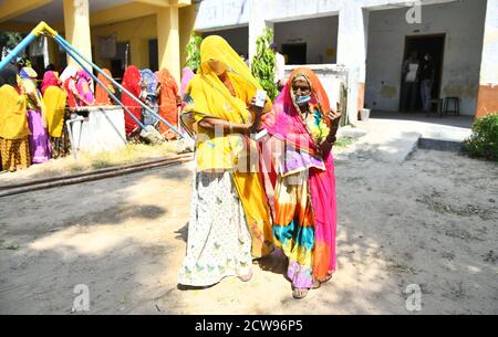 Beawar, Rajasthan, India, 28 settembre 2020: Un'anziana votatrice di donna Bardi Devi mostra il suo ID Voter e ha inked il dito dopo il voto del cast con la sua nuora durante le elezioni di Panchayati Raj, in mezzo alla pandemia di coronavirus in corso, nel villaggio di Sendra vicino a Beawar. Oltre il 83.50 per cento degli elettori del 31.95-lakh hanno espresso i loro voti nella prima fase di 947 grammi Panchayat (Consiglio del Villaggio) elezioni in 25 distretti in tutto lo stato. Le linee guida relative al COVID-19 non sono state seguite durante le elezioni. Gli elettori indossano maschere facciali ma non hanno mantenuto la distanza sociale. Credit: Sumit Saraswat/Alamy Live News Foto Stock