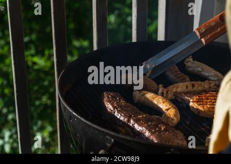 Primo piano di bistecche e salsicce cucinate all'aperto griglia Foto Stock