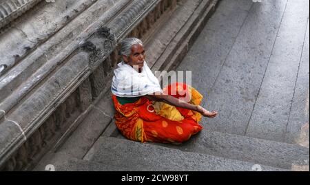 Anziana donna Beggars seduto all'interno di un tempio Foto Stock