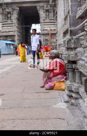 Anziana donna Beggars seduto all'interno di un tempio Foto Stock