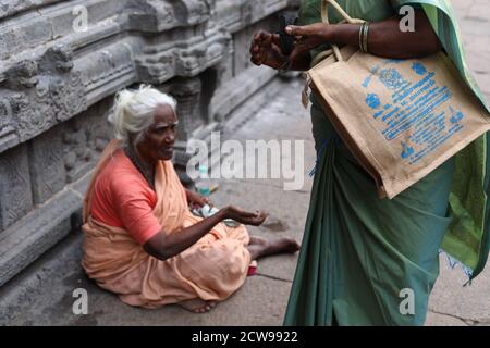 Anziana donna Beggars seduto all'interno di un tempio Foto Stock