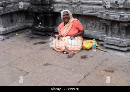 Anziana donna Beggars seduto all'interno di un tempio Foto Stock