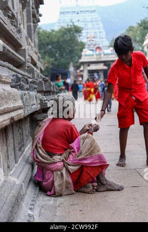 Anziana donna Beggars seduto all'interno di un tempio Foto Stock