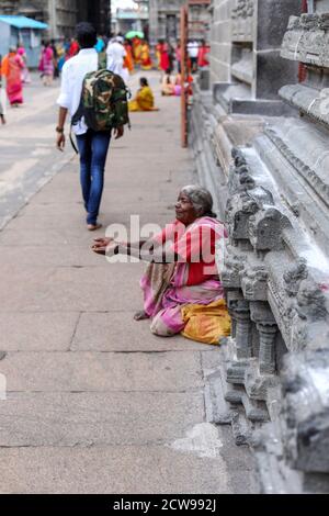 Anziana donna Beggars seduto all'interno di un tempio Foto Stock