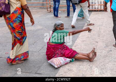 Anziana donna Beggars seduto all'interno di un tempio Foto Stock