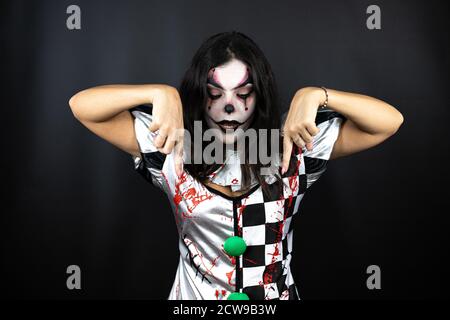 donna in un costume halloween clown su sfondo nero isolato sorpreso, guardando la fotocamera e puntando con le dita e braccia sollevate Foto Stock