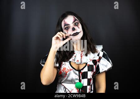 donna in un costume di clown halloween su bocca di fondo nera isolata e le labbra chiuse come zip con le dita. Segreto e silenzioso, tabù che parla Foto Stock