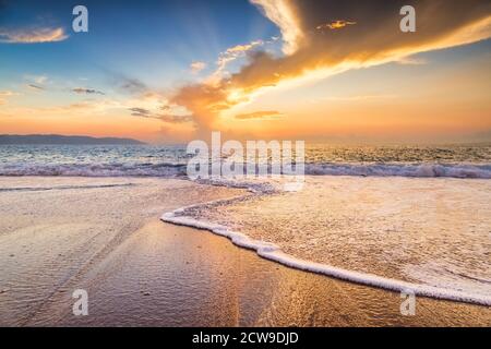 Un'onda dell'oceano di tramonto sta rompendo sulla costa del mare con l'impostazione del sole sull'orizzonte dell'oceano Foto Stock