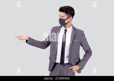 Ritratto giovane uomo d'affari asiatico in abito da indossare maschera facciale per protezione covid-19 isolato su sfondo bianco, uomo d'affari presentare e mostrare, Foto Stock