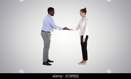L'uomo africano e la donna caucasica che danno basso cinque su gradiente indietro Foto Stock