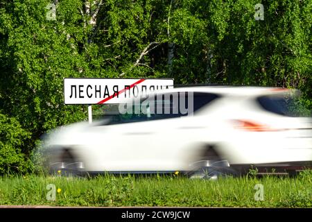 Segnaletica stradale fine della città Lesnaya Polyana o Forest Glade, una città satellite di Kemerovo, verde foresta, erba e bianco avto Foto Stock