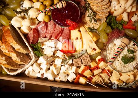 Tavola di formaggio servita con formaggi tipo Manchego, salame, formaggio fresco, casetta, uva, formaggio Oaxaca, pane alle erbe fresche, rosmarino e prezzemolo f Foto Stock