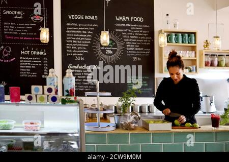 Un lavoratore dedicato o un imprenditore che prepara diligentemente il cibo dietro il bancone di un bar moderno o di un ristorante salutare. Foto Stock