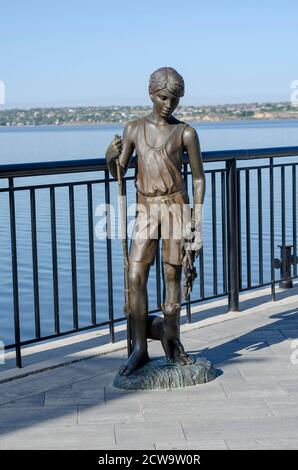 Nikolaev, Ucraina - 20 settembre 2020: Statua di bronzo di un ragazzo con un pesce goto e un gatto. Terrapieno della città del fiume Bug meridionale. Un bene-maintaine Foto Stock