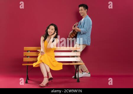 Suonare la chitarra nel giovane e ascoltare la musica delle giovani donne Foto Stock