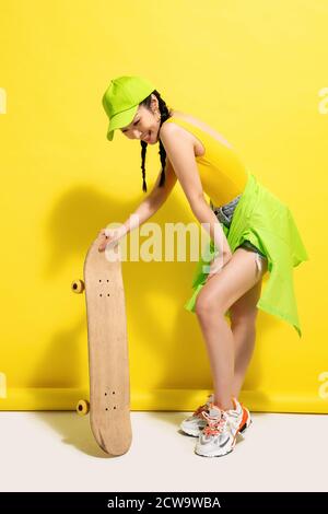 Ragazza giovane che tiene skateboard Foto Stock