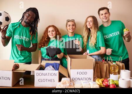 diversi volontari si impacchettano, raccolgono gli aiuti umanitari nella scatola delle donazioni. gruppo multietnico di persone che lavorano in fondazione caritativa per aiutare in crisi e senza tetto Foto Stock