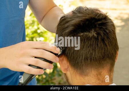 il barbiere taglia il ragazzo con un regolacapelli Foto Stock