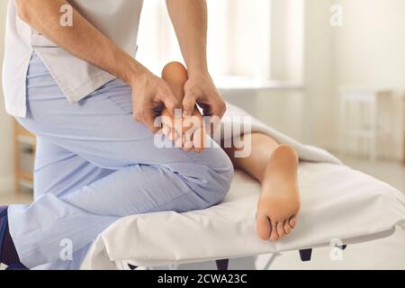 Massaggiatore maschile professionista che fa massaggio ai piedi per la giovane donna in moderno centro benessere Foto Stock