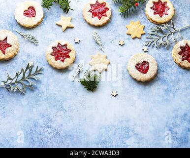 Biscotti Linzer di Natale o Capodanno riempiti con marmellata e spolverati con zucchero in polvere su sfondo blu. Biscotti tradizionali austriaci di Natale. Festivo Foto Stock