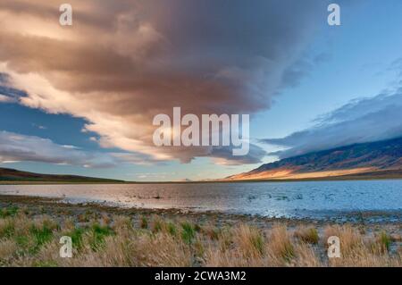 Enorme nuvola di fronte a Steens Mountain, che sorge a 5,000 metri sopra il lago Mann, all'alba, Alvord Desert, parte del Great Basin Desert, Oregon, USA Foto Stock