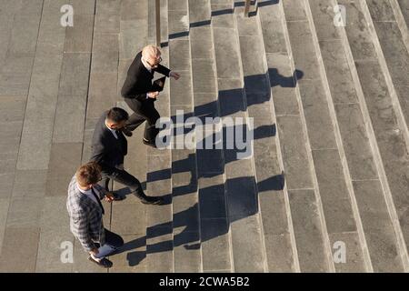 Vista ad alto angolo degli uomini d'affari che saliscono le scale insieme in città Foto Stock