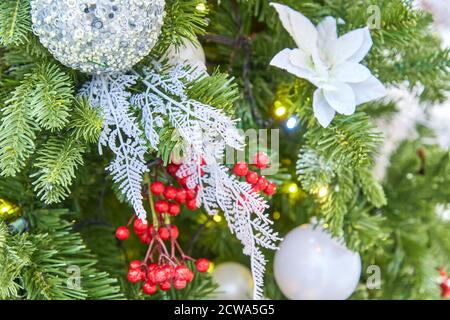primo piano di albero di natale decorato con palline scintillanti d'argento e ghirlanda con luci accese. Sfondo festivo con spazio di copia per i tuoi progetti Foto Stock