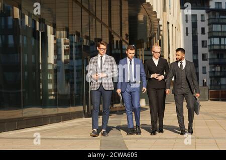 Gruppo di uomini d'affari che discutono di lavoro mentre camminano lungo il via della città Foto Stock