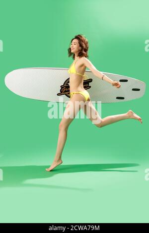In una bellezza bikini con una tavola da surf Foto Stock