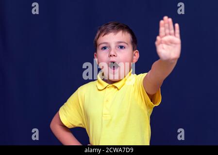 Giovane caucasico a bocca aperta 9 s ragazzo mettendo la mano fuori facendo segno di stop Gesture.Blue sfondo studio. Foto Stock